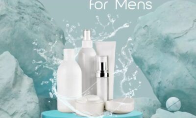 Skin care products for men displayed on a blue platform with water splash effect and marble-textured background.