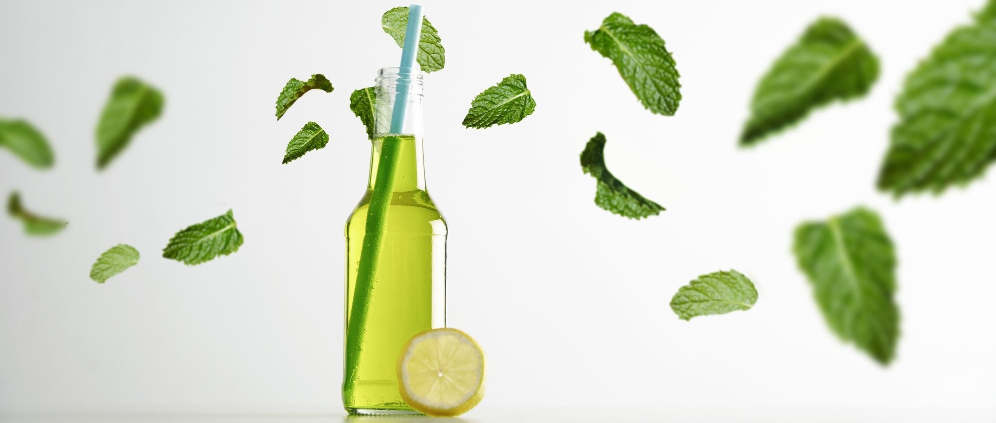A refreshing bottle with green liquid, surrounded by floating mint leaves and a lemon slice, symbolizing the natural benefits of lemon balm.
