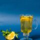 Lemon Balm benefits shown in a glass of herbal tea with lemon slices and mint leaves, styled on a blue background for a wellness vibe.