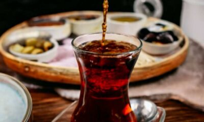 Pouring black tea into a glass, showcasing the rich color, highlighting the Health Benefits of Black Tea like improved heart health.