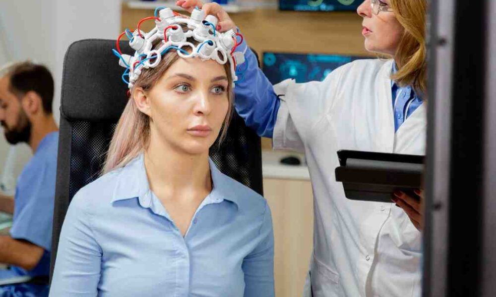 Neuropsychological testing in progress with an EEG cap being adjusted by a doctor, displaying brain analysis data on screen.