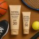 Two tubes of natural sunscreen for sports athletes with SPF 30 and 50, surrounded by tennis gear and a basketball.